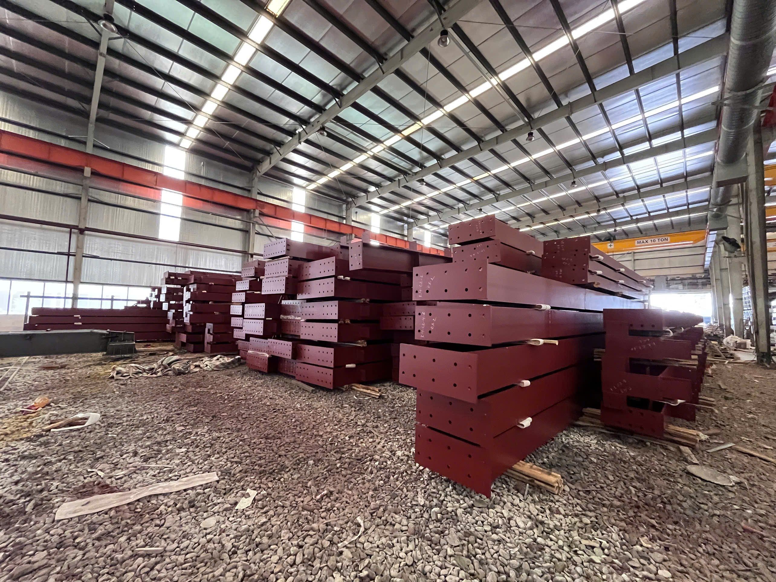 Cấu kiện thép phủ lớp sơn lót đỏ xếp chồng trong nhà xưởng