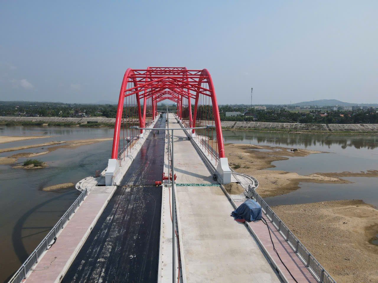 Cầu vòm thép sơn đỏ bắc qua sông, chụp từ xa